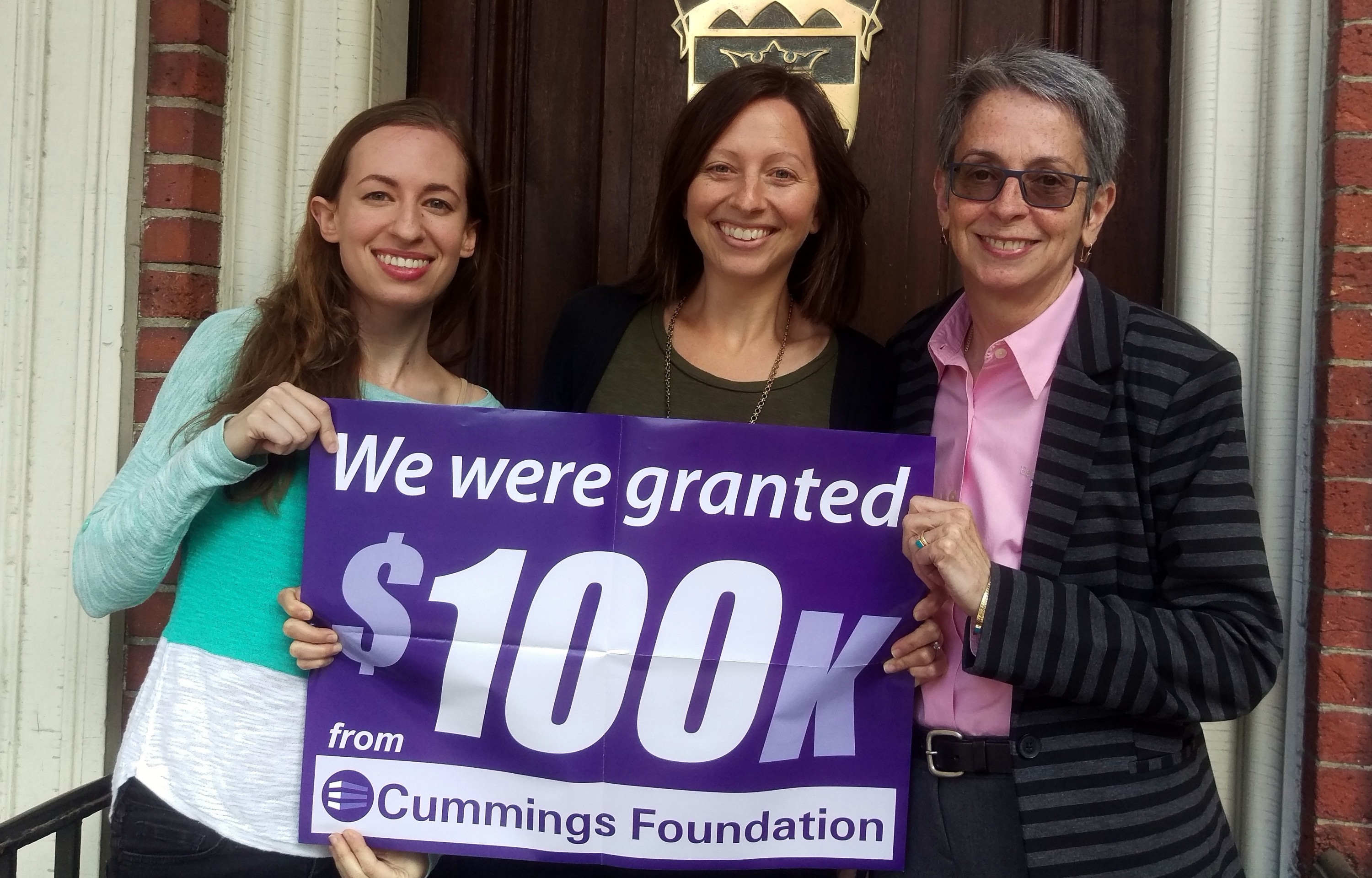 Clearinghouse staff hold the poster announcing their grant from Cummings Foundation. L to R: Communications Coordinator Hilary Vaught, Access to Justice Fellows Program Director Mia Friedman, and Executive Director Maribeth Perry. 